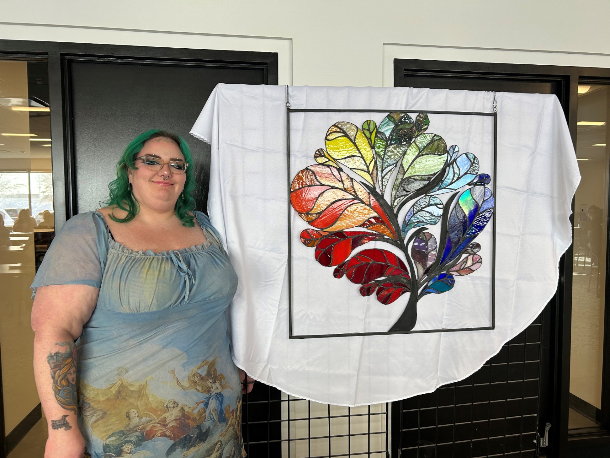 Stained glass artist Justine Hickey with colourful Safer Spaces Tree art.